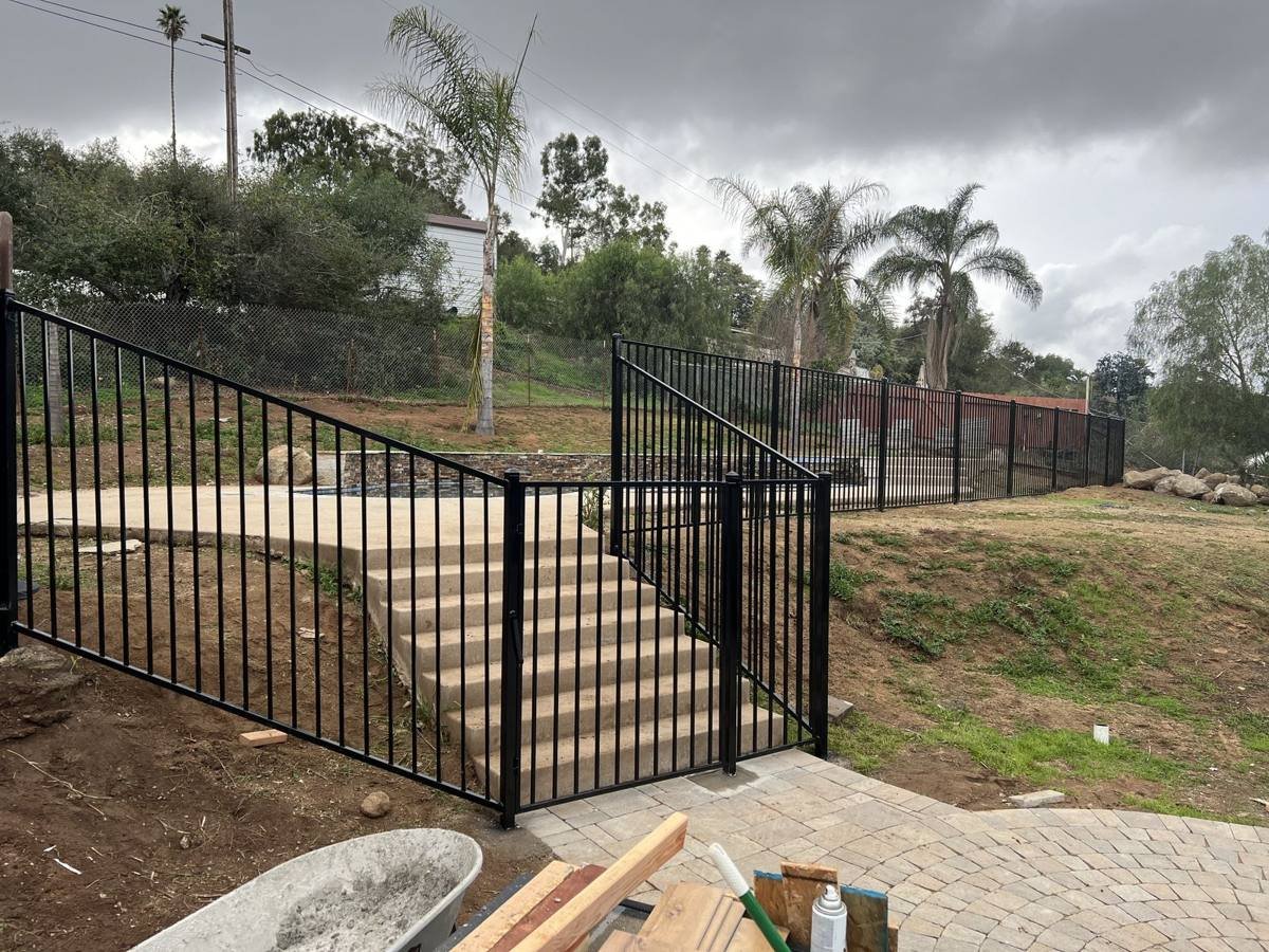 Iron fence and gate along backyard steps to a pool