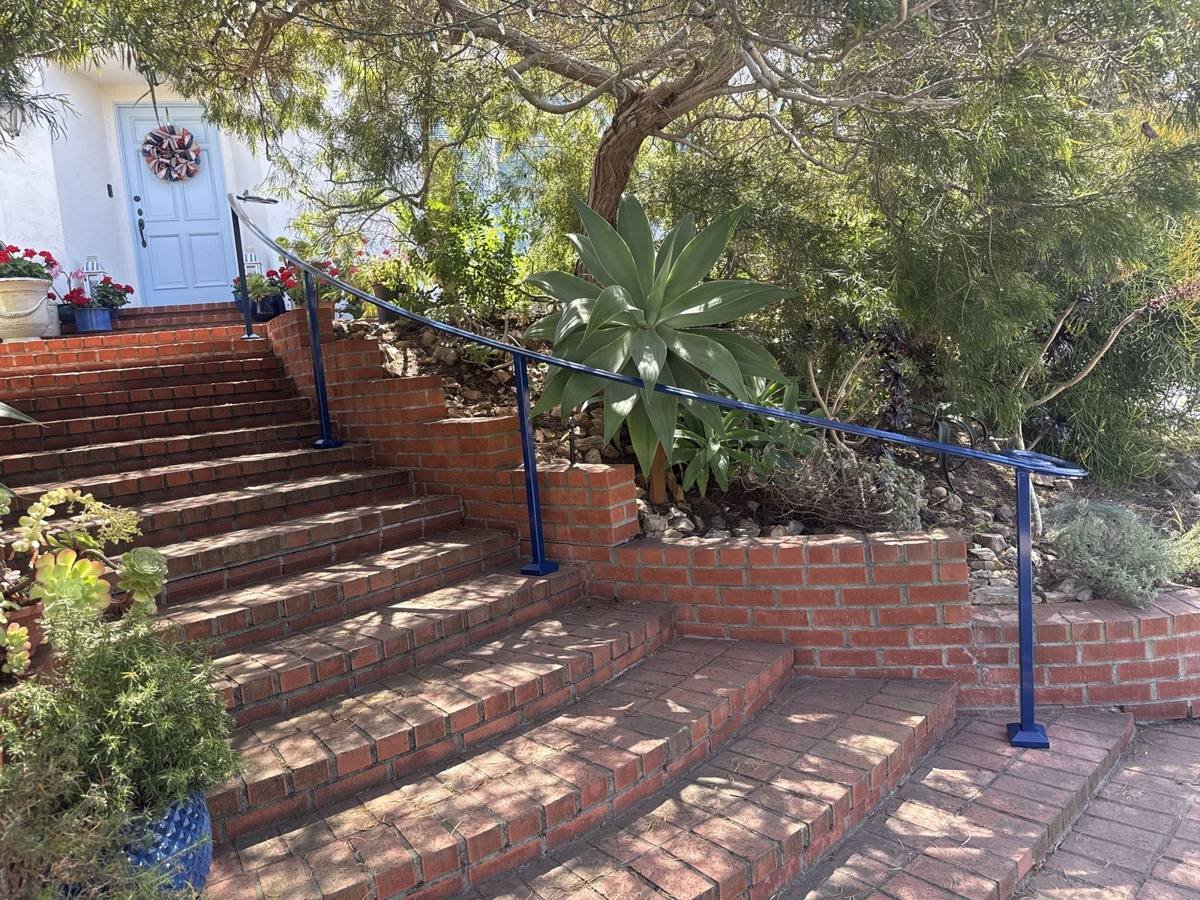 Curved blue handrail on brick garden stairs