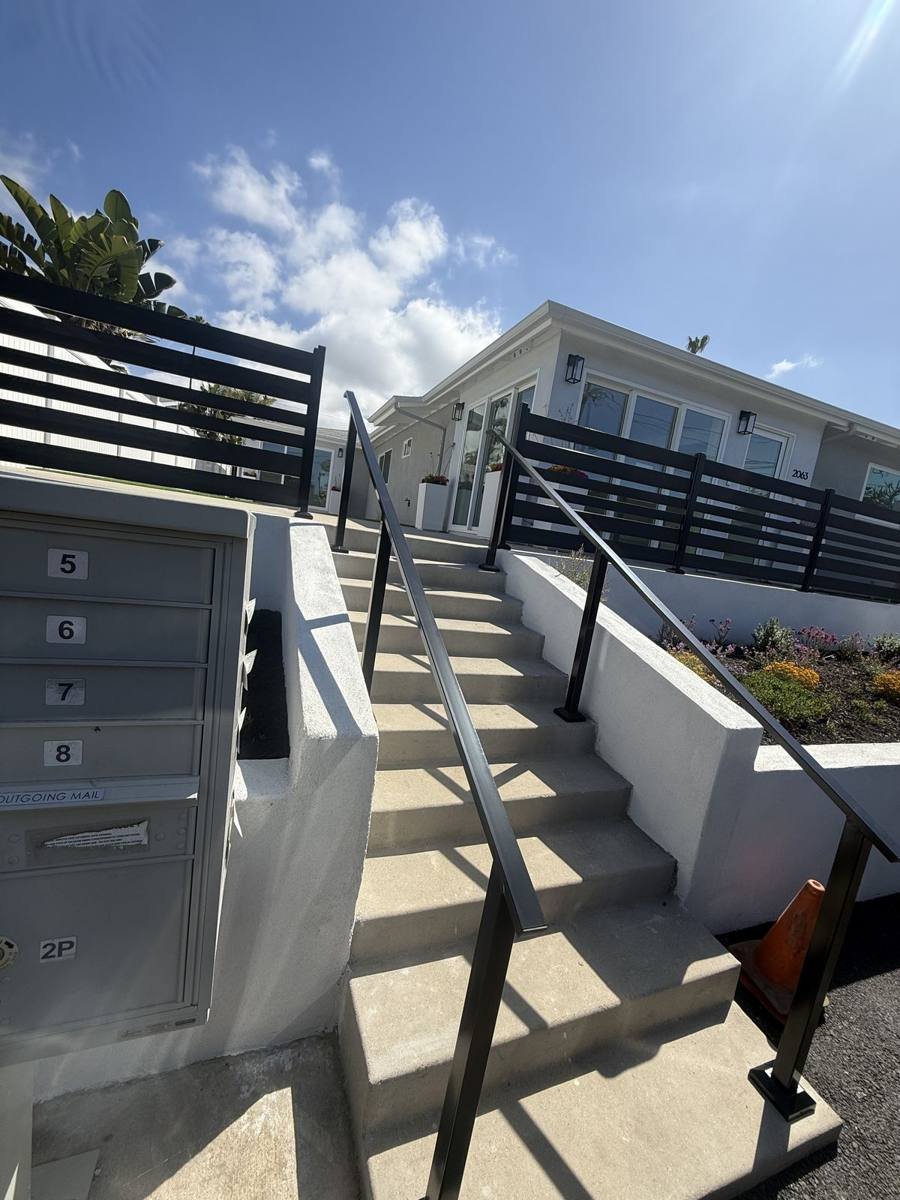 Black handrails on entry steps with a horizontal-slat fence